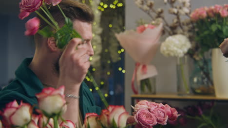 male professional florist seller collects bouquet for customer in flower shop