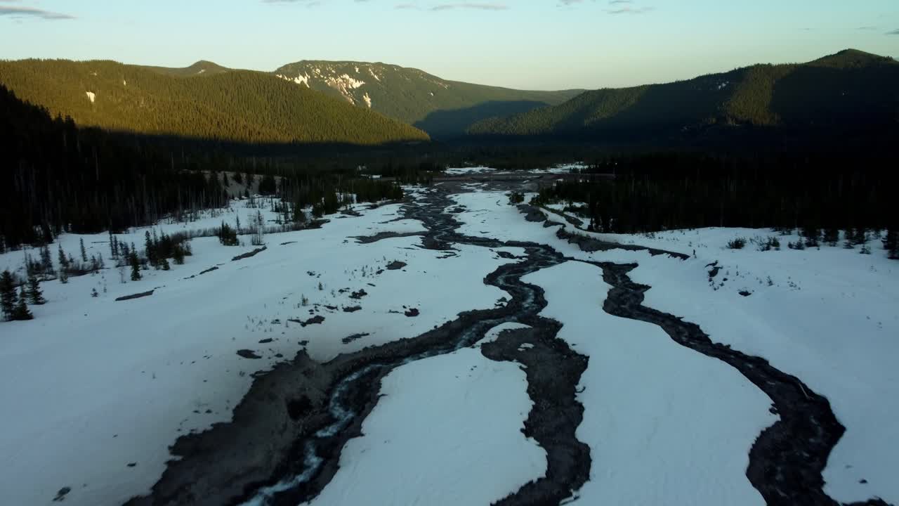 US, Oregon, Mt Hood, White River, 2025-04-22 - Drone view of the White River near Mt Hood in spring, with snow still covering the creek and trees with the highway bridge in the center