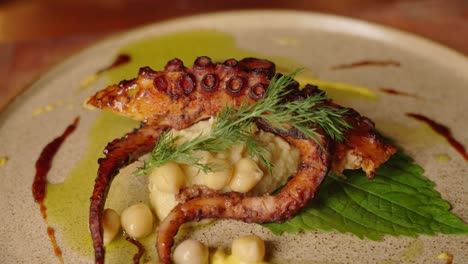 Primer-Plano-De-Cámara-Lenta-De-Un-Plato-Completo-De-Pulpo-A-La-Parrilla-Con-Ensalada-De-Garbanzos,-Bellamente-Adornado-Y-Chapado-Con-Un-Concepto-De-Cocina-Estética