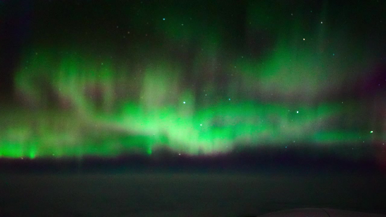 Splendida aurora boreale verde che luccica in un cielo notturno scuro e stellato. Fenomeno naturale cinematografico adatto per documentari scientifici, di viaggio e sul benessere.