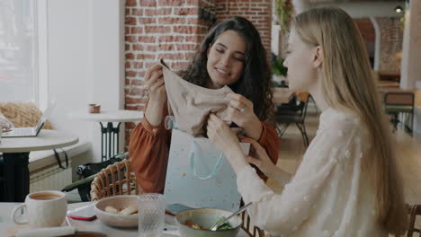 two women celebrating a gift in a cafe