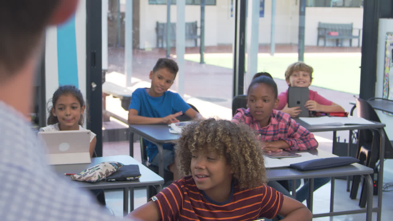 Elementary students looking to teacher, over shoulder view