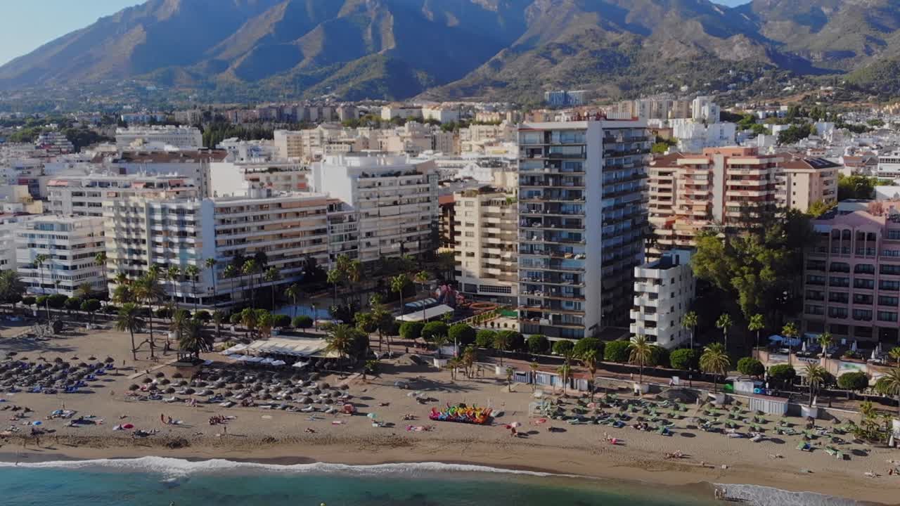 drone filmado moviéndose de lado filmando los edificios frente a la playa en marbella, españa