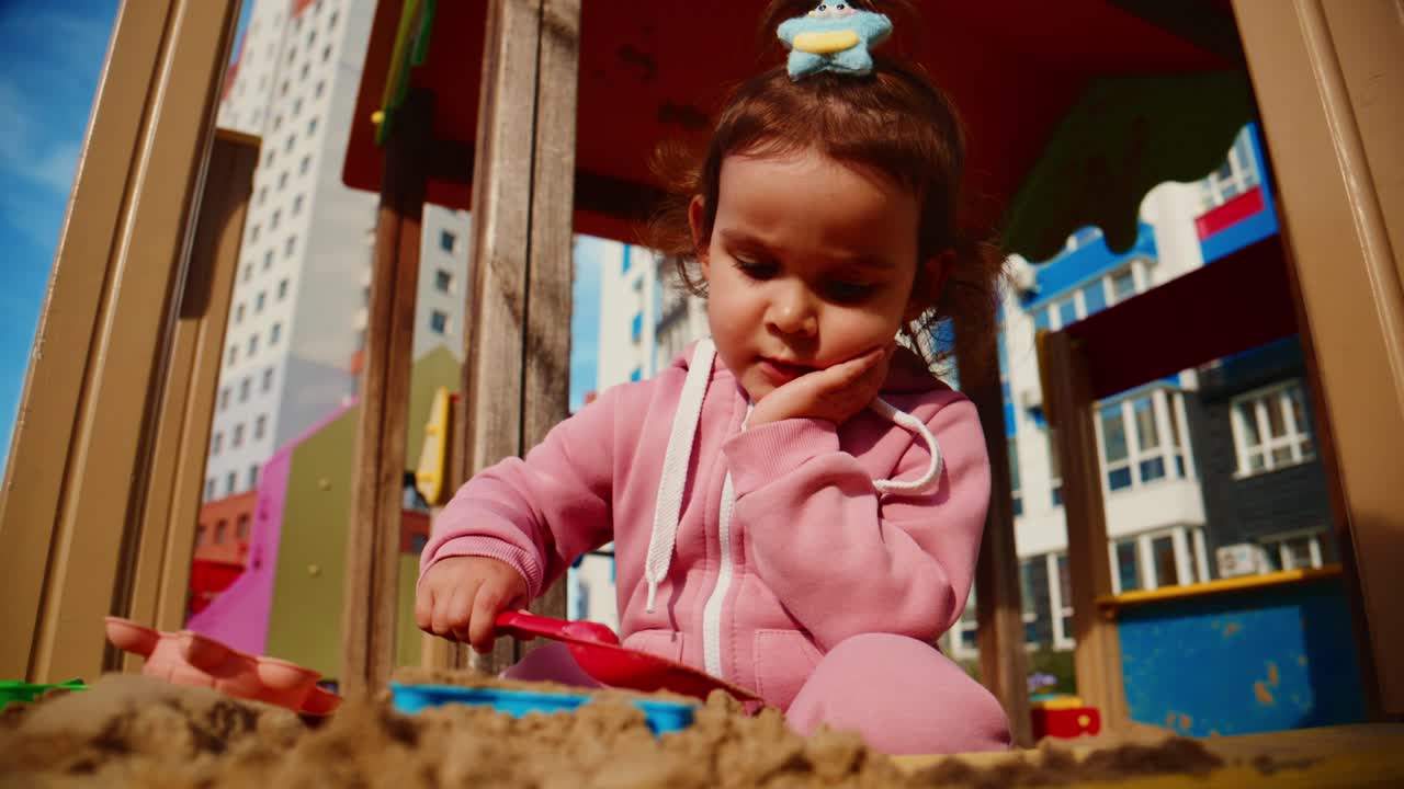 A young child explores creativity and play in a vibrant sandbox, showcasing joy and curiosity while using colorful toys in an engaging outdoor environment