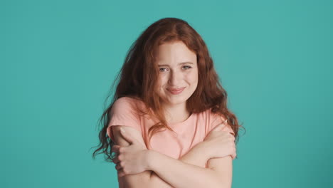 Redheaded-girl-looking-at-camera-on-turquoise-background.