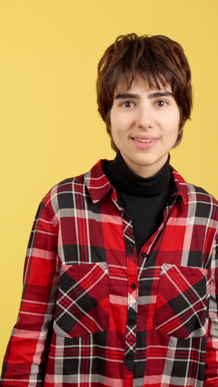 Young person expressing excitement and joy in a plaid shirt against a yellow background