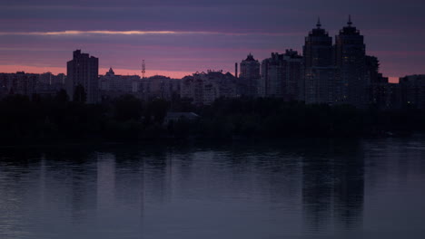 Evening-cityscape-at-purple-sky-drone-shot.-Calm-river-reflecting-constructions.