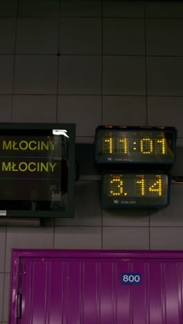 metro station platform with time displays and młociny sign