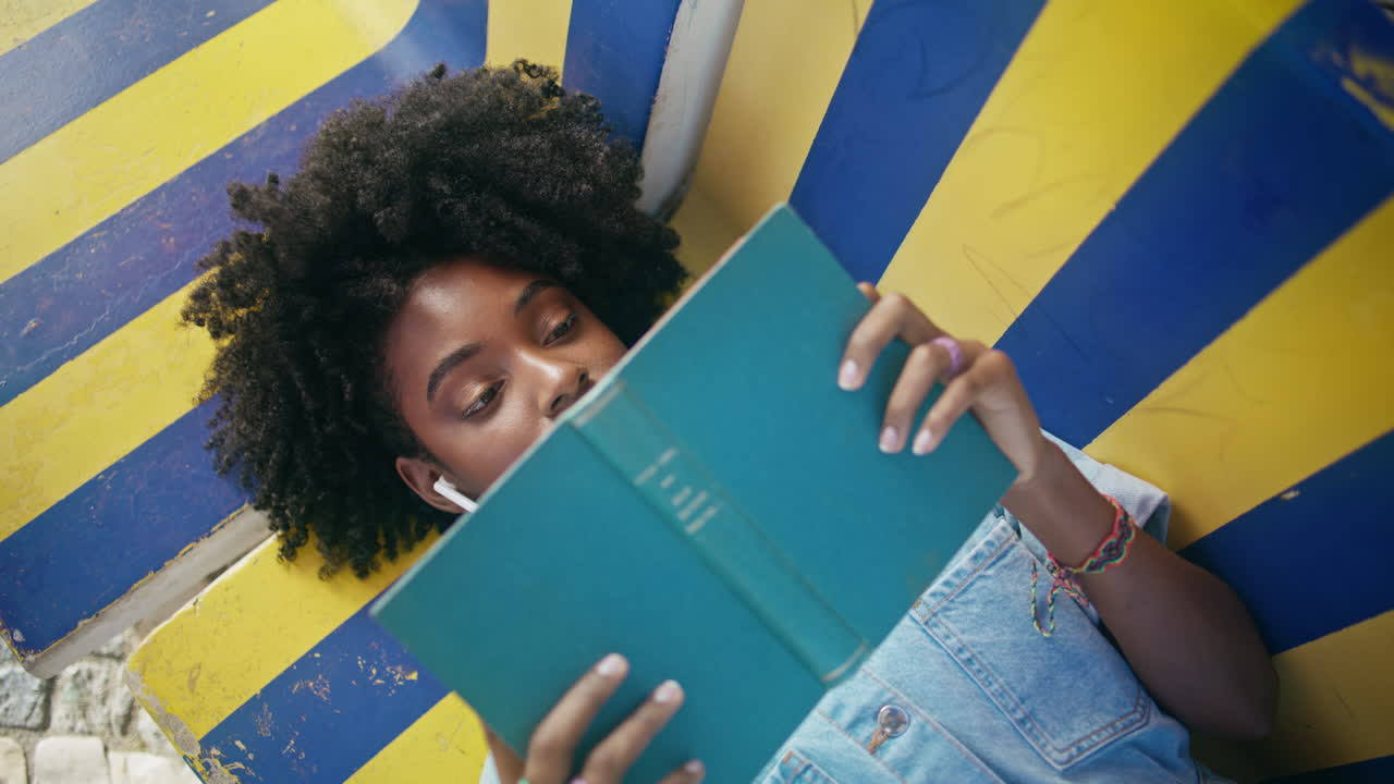 estudiante de libro acostado banco de aprendizaje tarea universitaria primer plano. chica escondiendo libro de texto