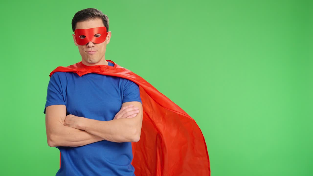 Superhero posing with crossed arms on green screen