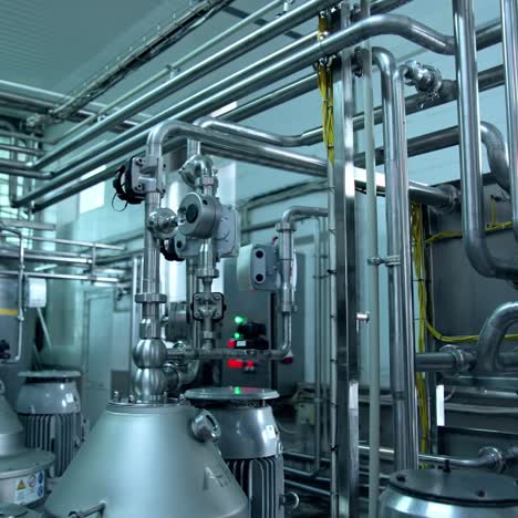 big cisterns for storing and fermenting milk at diary factory. stainless steel pipes crossing and connecting reservoirs with each other. close up