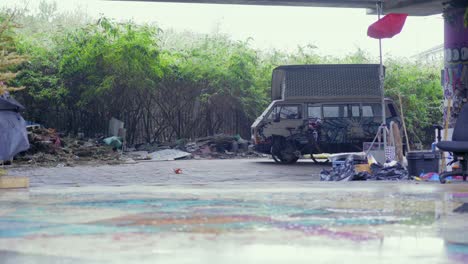 rain pouring on a camping van in a trashed homeless camp with graffiti arts on walls and ground