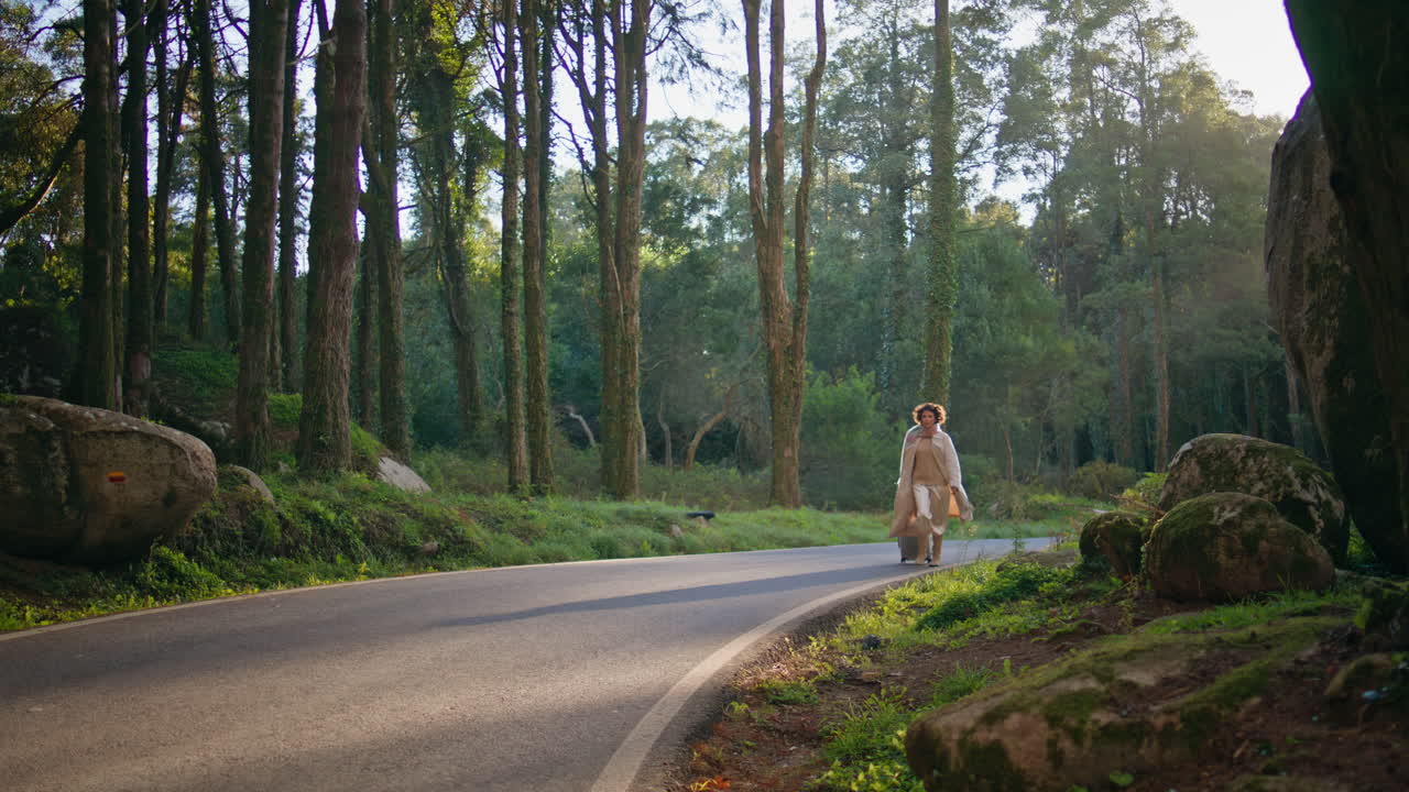 소녀가 가방과 함께 빛에 자연 도로를 산책합니다. 여성 탐험가 고 있습니다.