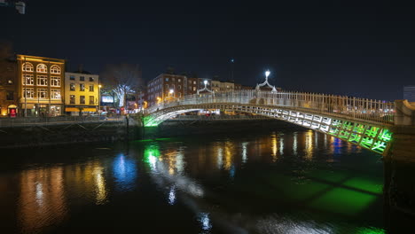 time lapse of nighttime road traffic and people walking over the historical bridge on liffey river in dublin city centre in ireland.