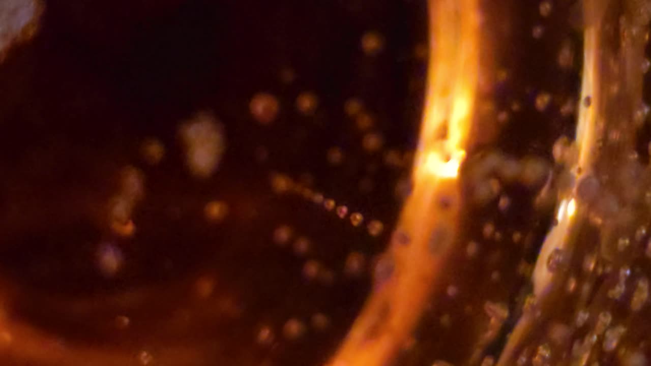 Golden bubbles swirl and rise inside a glass of sparkling wine. Abstract macro view highlighting effervescent texture and rich color.