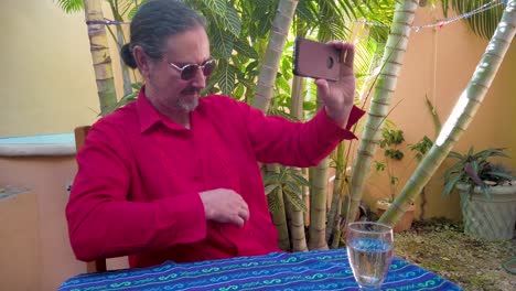 mature man responding to someone on smartphone, shows off his guayabera shirt