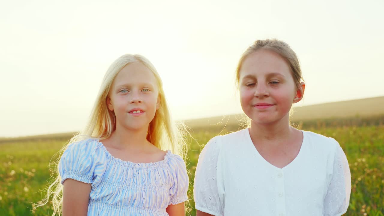 Dos niñas sonriendo a la cámara en un campo soleado de verano