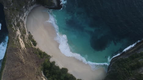 Hermosa-Playa-Tropical-Aérea-Del-Paraíso-Vacacional---Vista-De-Pájaro-De-Las-Olas-Del-Océano-Rompiendo-En-Una-Playa-Vacía-Rodeada-De-Acantilados-Desde-Arriba