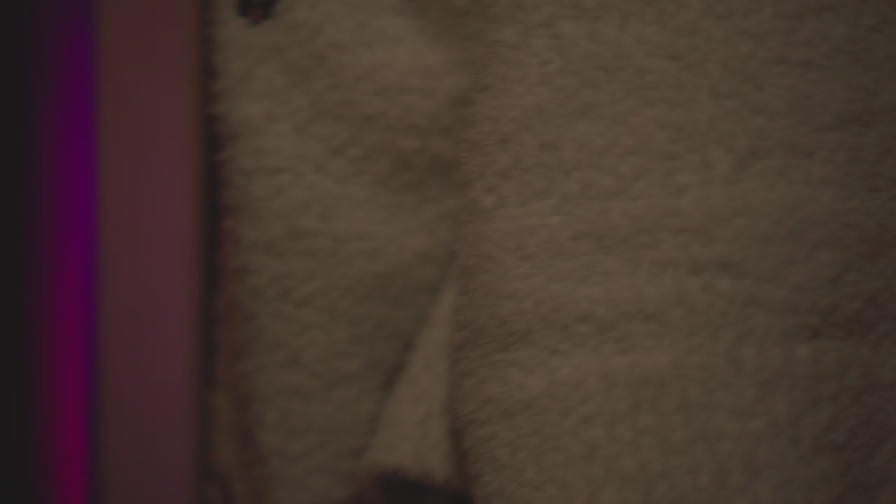 Close up metallic door handle turning open on dark frame revealing vibrant neon lit game room with pink purple and blue hues as person silhouette steps inside through ajar door under moody glow