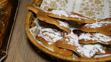 Beautiful-woman-is-putting-freshly-cooked-gingerbread-cookies-with-sugar-powder-on-top-into-the-plate-for-eating