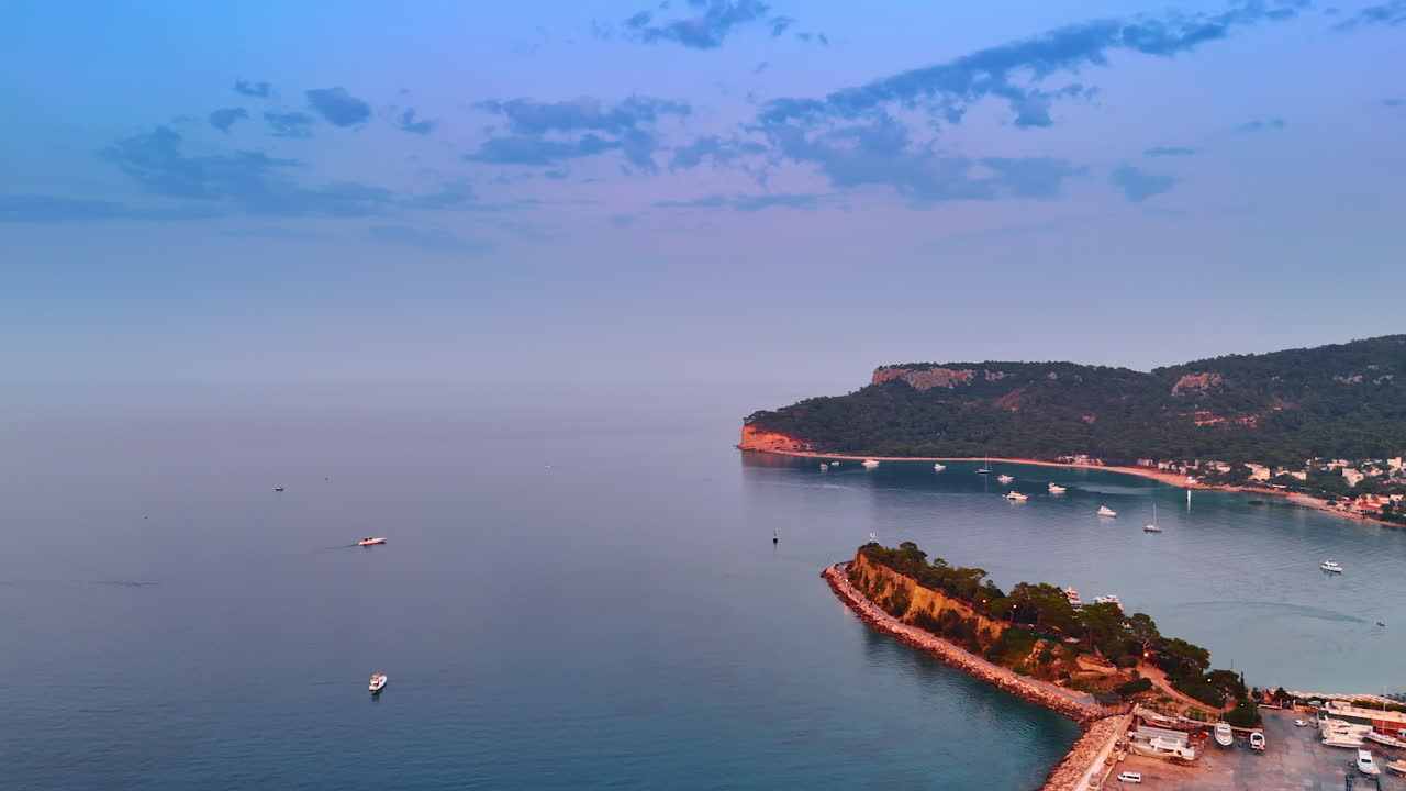 Amazing pink-blue waterscape of the Mediterranean at sunset. Beautiful white yachts are on the water. Rocky coast of Fethiye, Turkey from top view