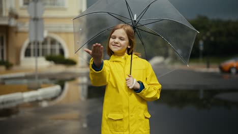 Blonde-teenage-girl-in-a-yellow-jacket-opens-an-umbrella-and-puts-out-her-hand-to-check-the-rain-while-walking-in-the-park