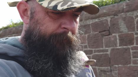 stressed bearded caucasian male wearing baseball cap walking alongside wall