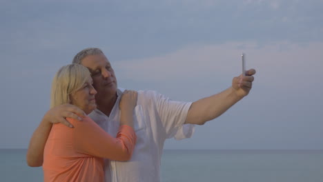 una pareja de mayores haciendo selfies de vacaciones en el móvil.