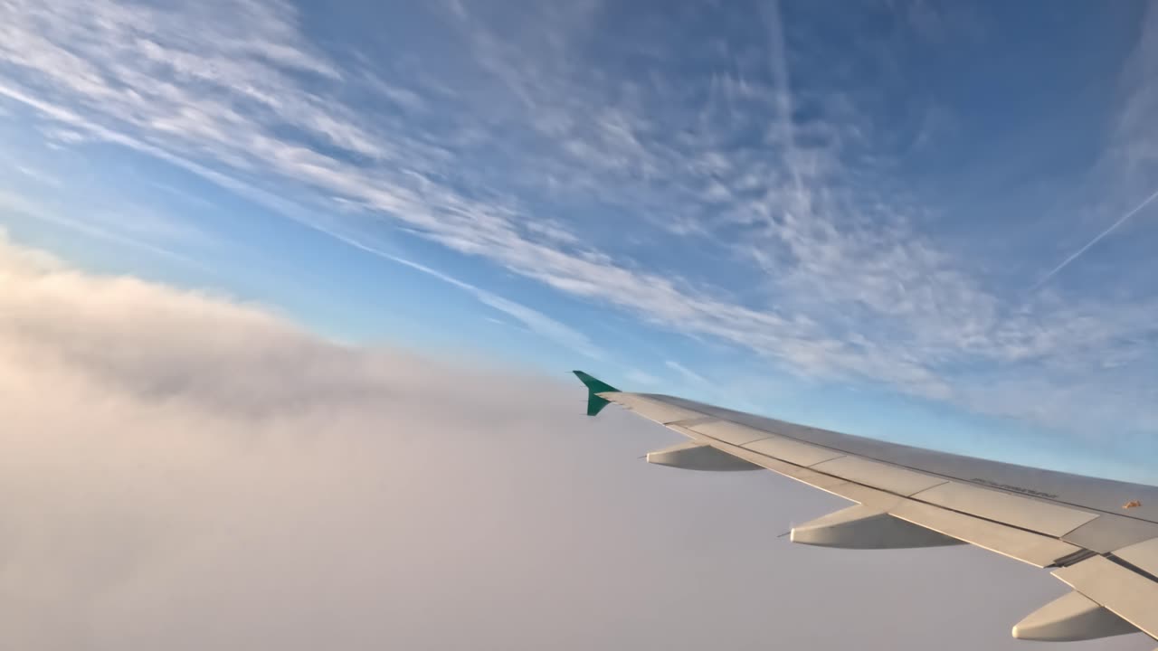 Looking out of the plane window as it ascends through clouds, gaining altitude.