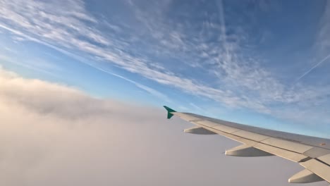 Looking out of the plane window as it ascends through clouds, gaining altitude.