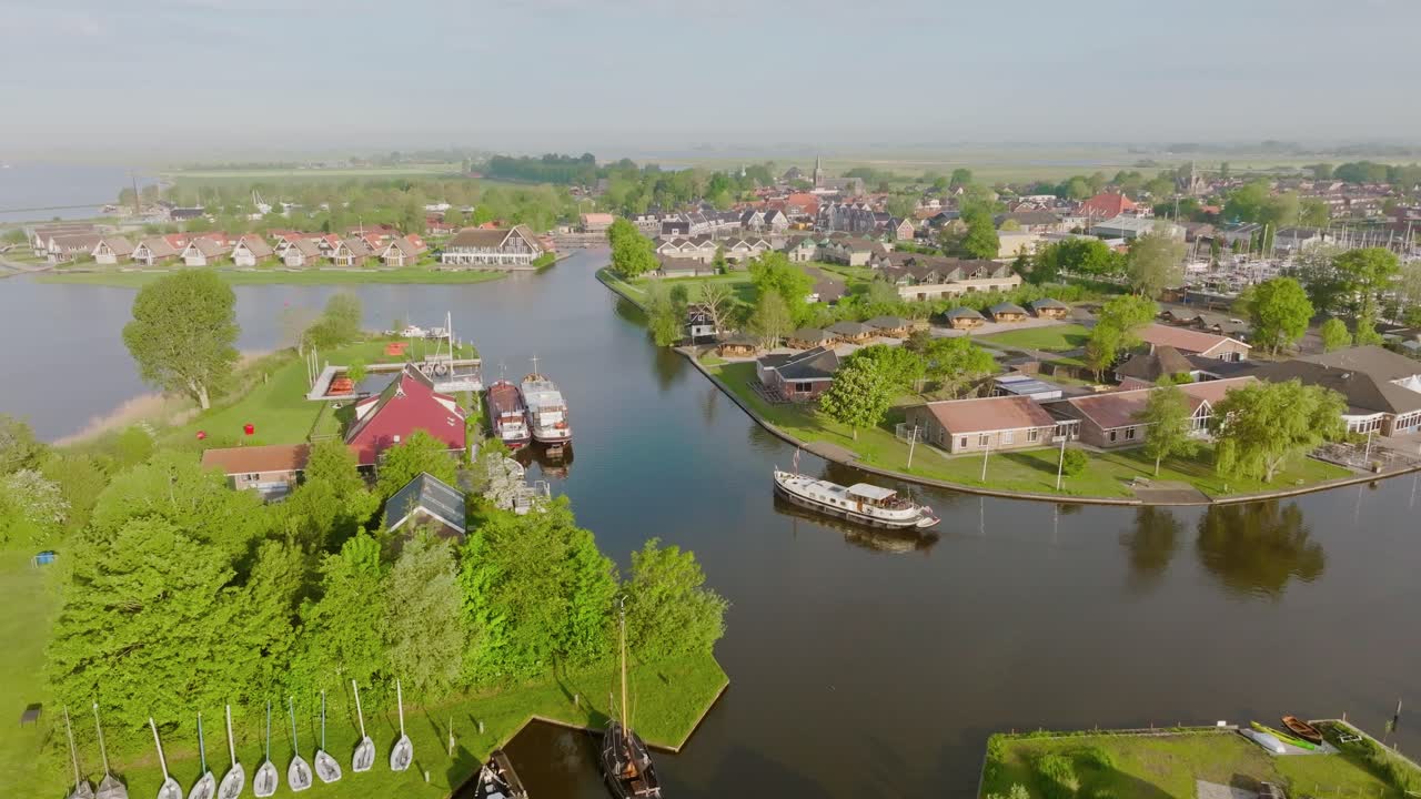 Aerial zoom in following a Luxemotor boat as it sails along the canal in Heeg, Netherlands, surrounded by waterfront houses