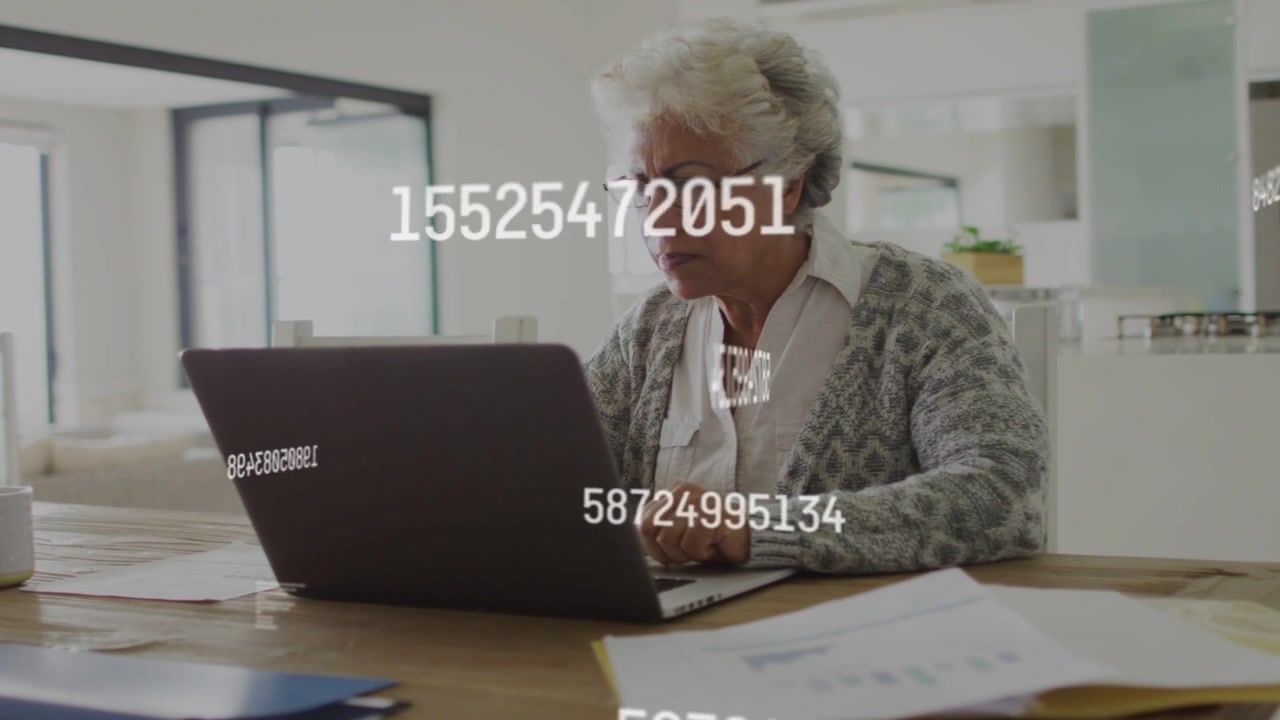 Donna anziana che digita al tavolo, con dati numerici che appaiono sullo schermo del laptop, rivelando documenti per la finanza.