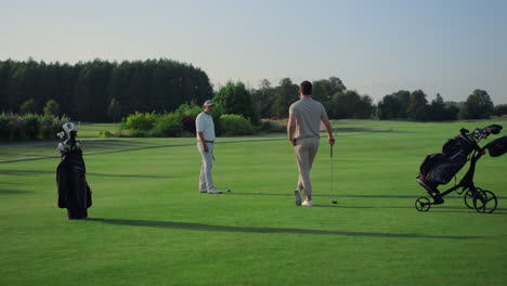 active men enjoy golf on course field. two golfers teeing play sport outside.