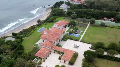 extravagant malibu mansion of oakley founder over cliffs of pacific ocean, aerial view