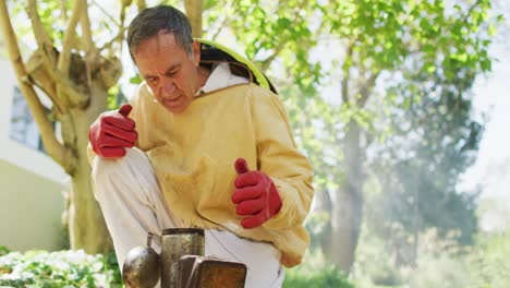 Caucasian-male-beekeeper-in-protective-clothing-preparing-smoker