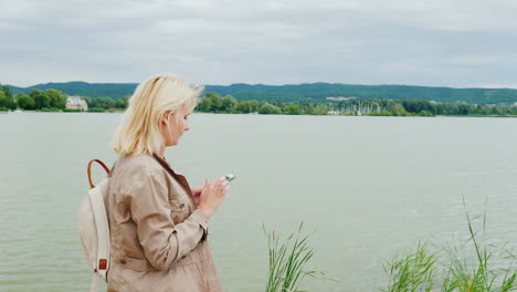 Woman-Walking-Around-Lake-With-Phone