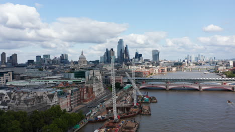 Forwards-fly-above-construction-site-of-Blackfriars-Bridge-Foreshore-at-Thames-river-bank.-Heading-towards-St-Pauls-Cathedral-and-skyscrapers-in-City-district.-London,-UK