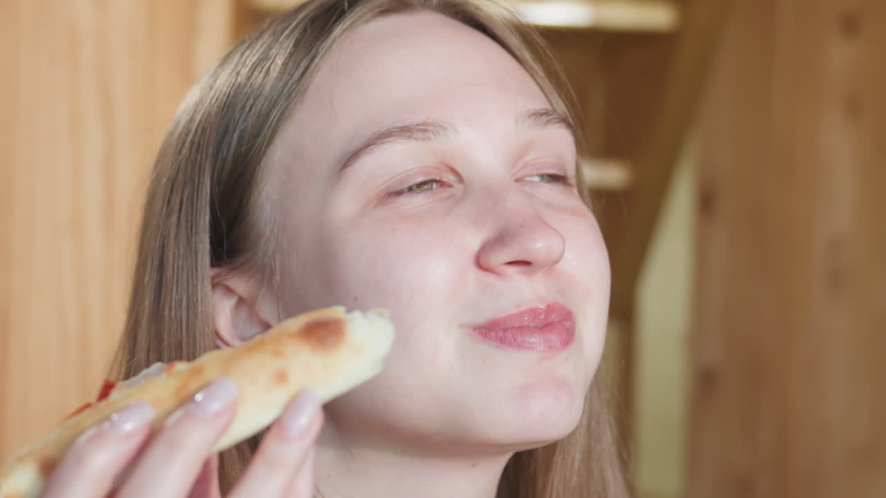 Close up of lady enjoying a slice of pizza with cheese, savoring the deliciousness with her eyes closed, she looks relaxed and delighted as she takes in the flavorful pizza