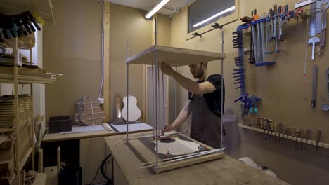 craftsman installing metal sticks while building guitar in workroom