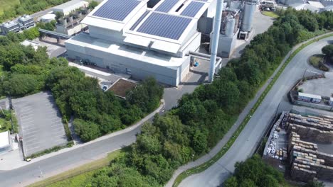 clean solar rooftop installation on modern office building aerial view with coal power station in background tilt up reveal shot