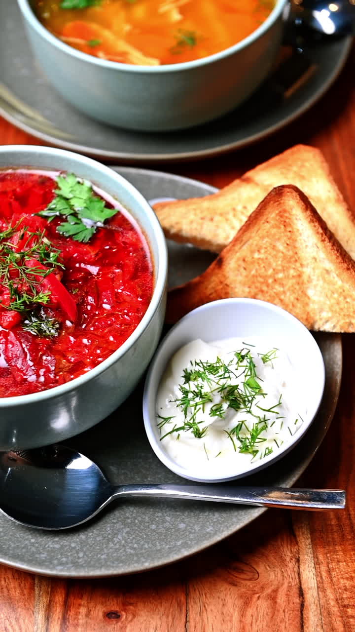 Traditional Ukrainian borscht with dill and parsley in ceramic bowl. Close-up of homemade red borscht soup served in a gray ceramic bowl with fresh herbs on top on wooden table