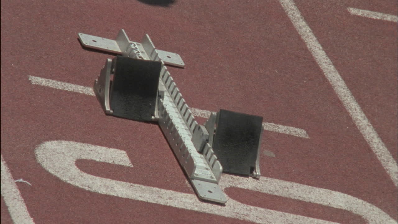 한 남자가 출발선의 블록에 위치를 잡습니다.