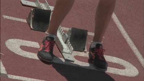 a man gets into position on the blocks at the starting line