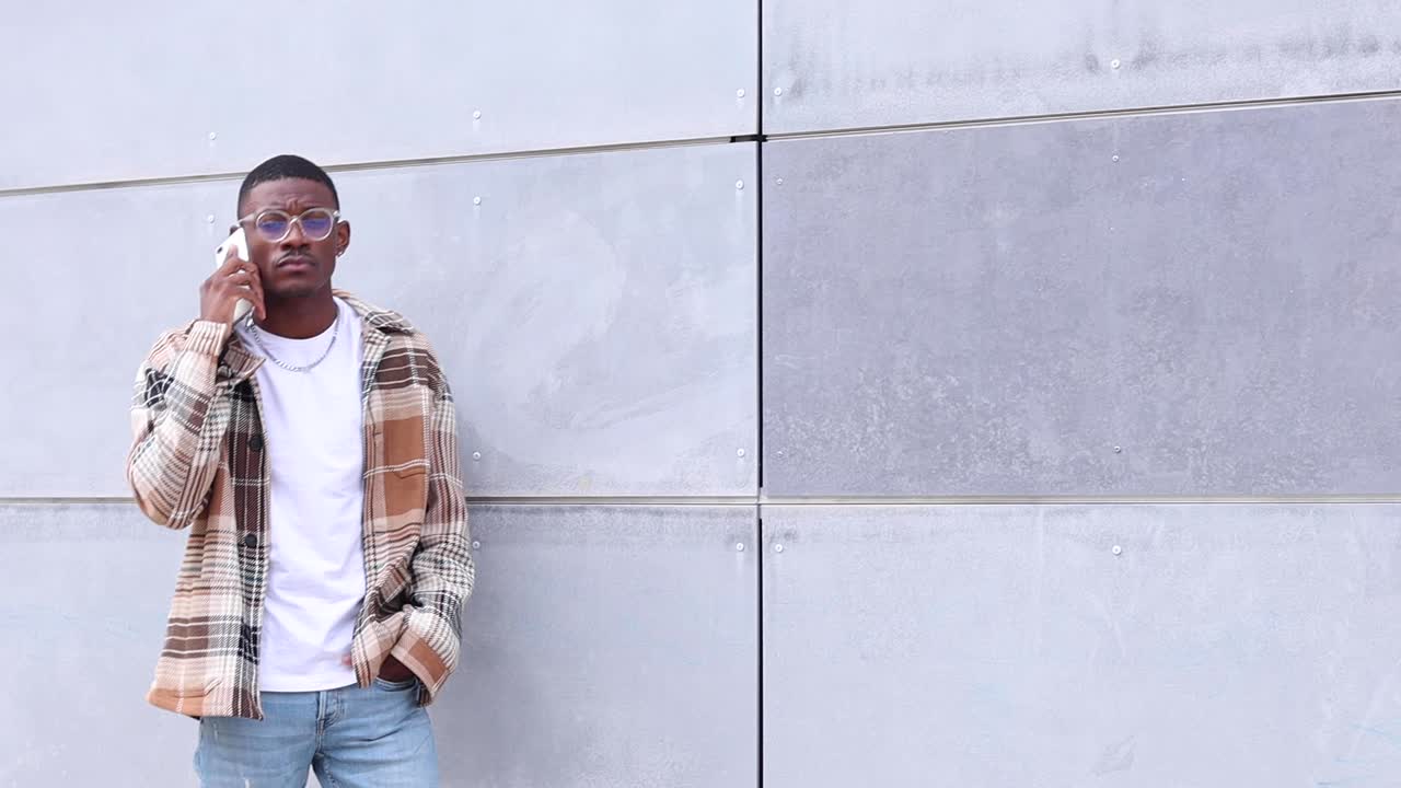 tipo étnico hablando en un teléfono inteligente cerca de la pared