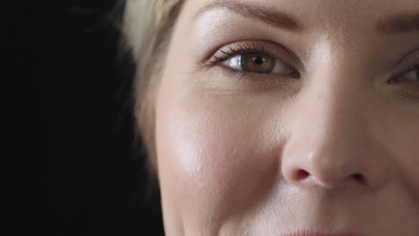 close-up-of-caucasian-woman-eye-looking-at-camera-smiling-happy-isolated-on-black-background-copy-space-half-face