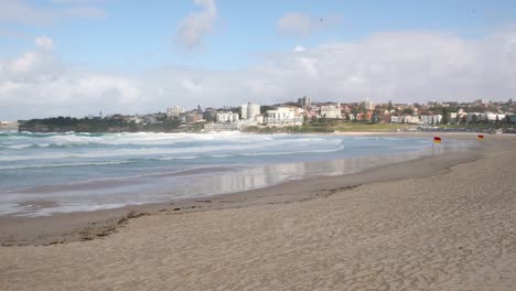 panning shot of wild windy surf with big waves on an empty beach in bondi sydney