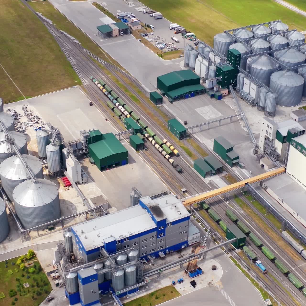 Industrial zone on field. Grain elevators for keeping and drying crop. Grain terminals and cargo trains carrying crop on a modern plant. Aerial view
