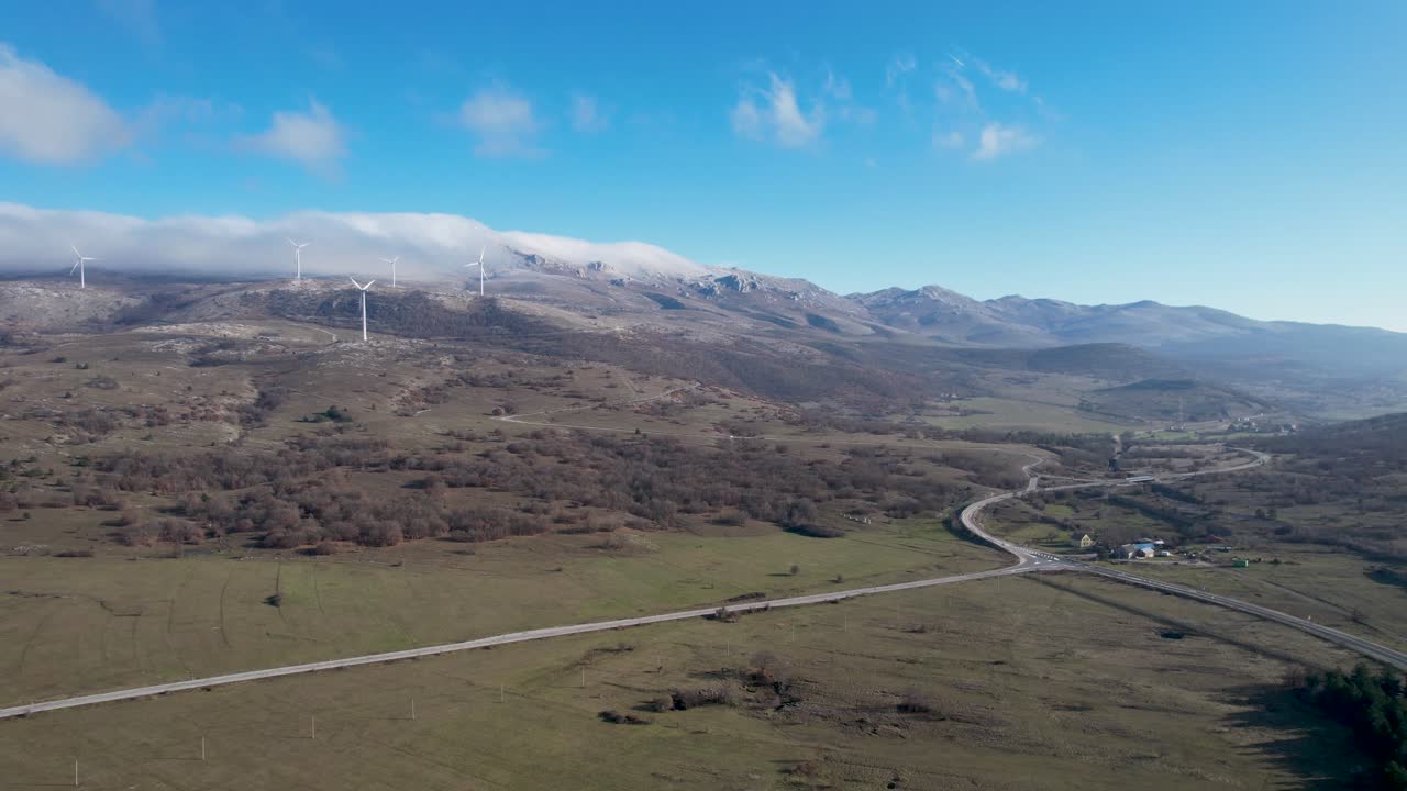 hermosa fotografía aérea del paisaje croata con turbinas eólicas que generan energía renovable en el fondo y una carretera vacía, en la región de liká en croacia, europa