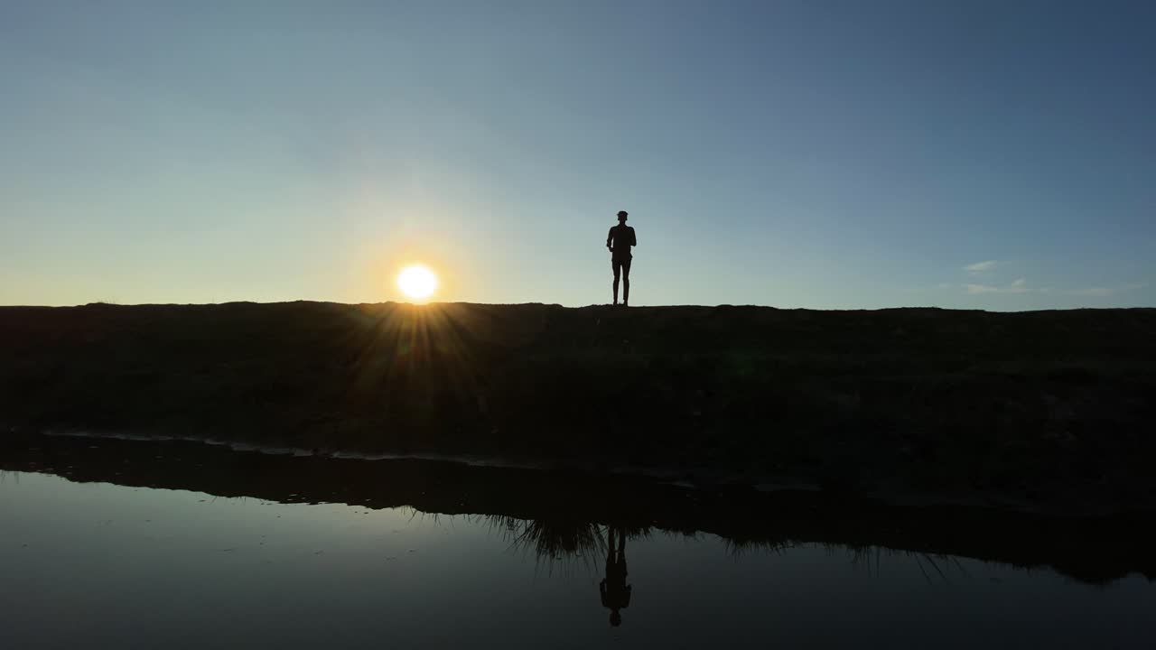 un joven flaco haciendo jogging al amanecer junto a un lago