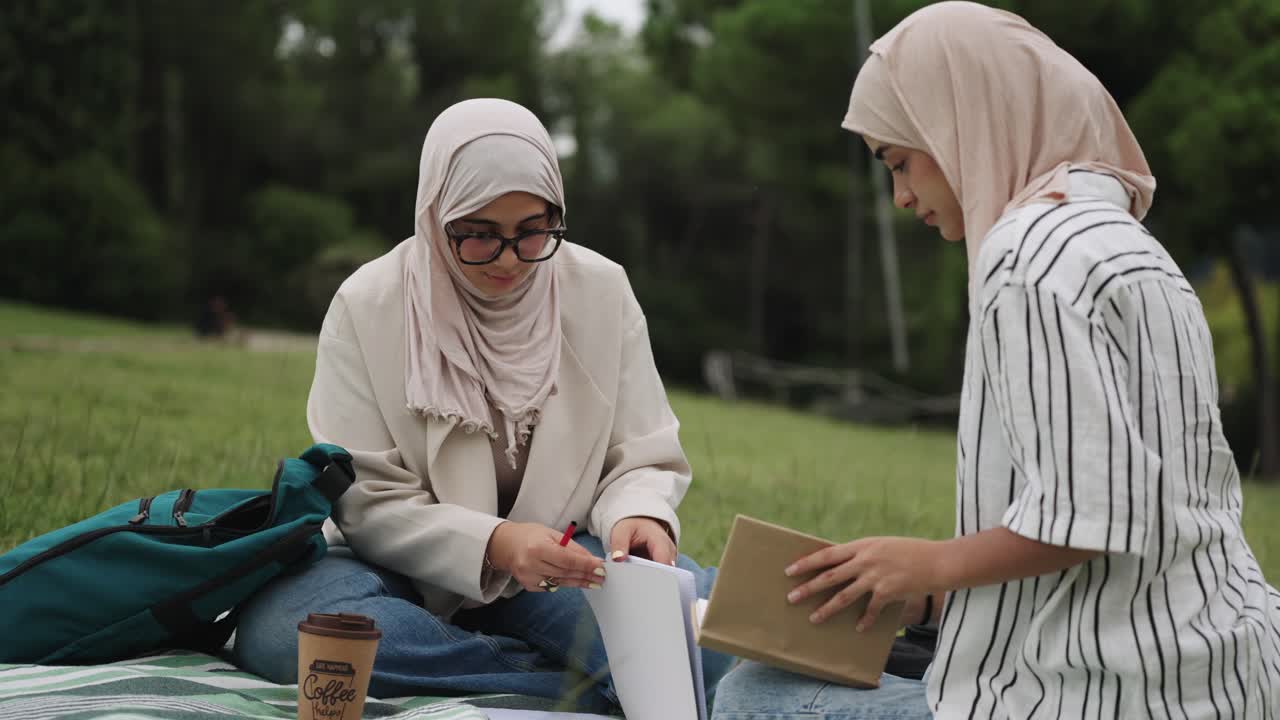 Two Muslim women studying together in the park